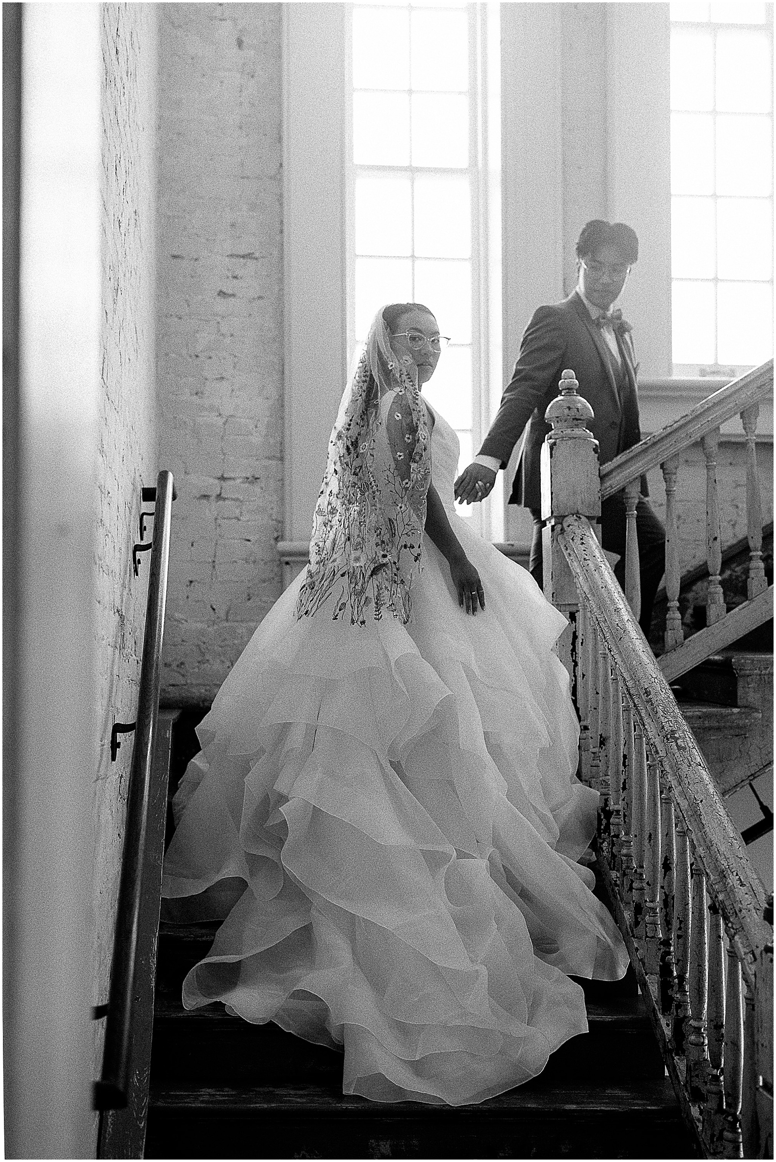 A groom leads a bride up a sunlit staircase inside Felicity Church New Orleans.