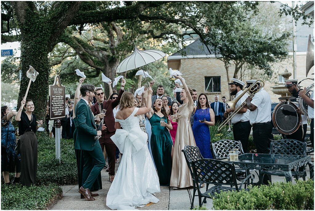 Wedding guests wave white handkerchiefs while a bride and groom dance at a New Orleans wedding venue.