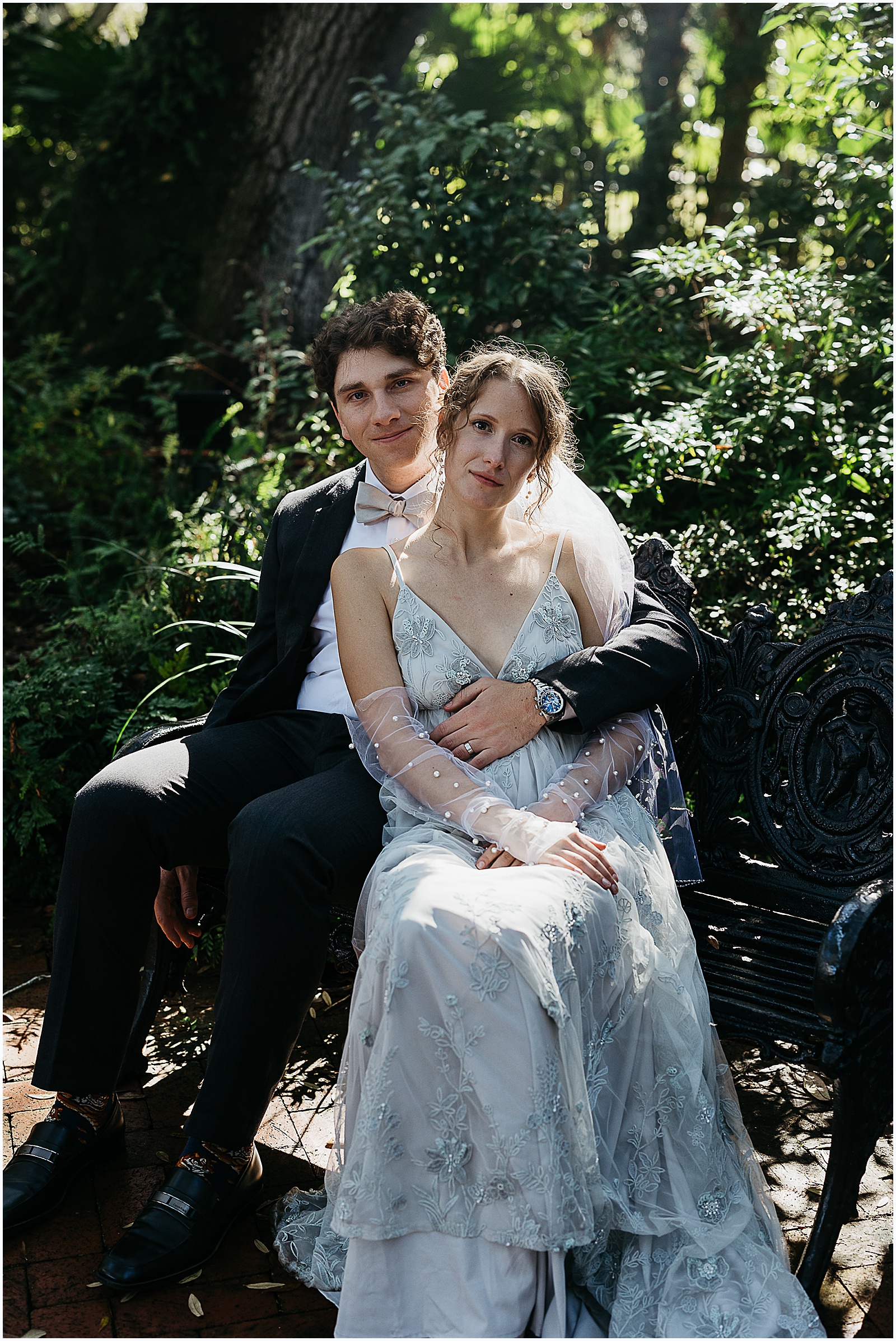 A bride and groom pose for winter wedding photos in a New Orleans garden.
