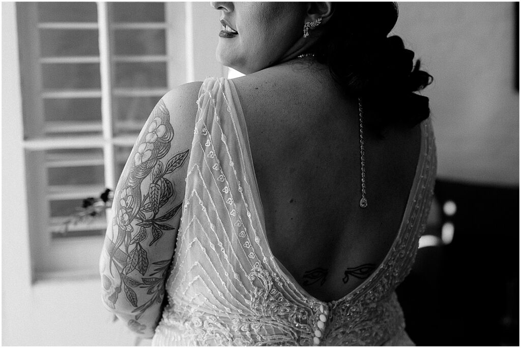 A black and white wedding photo shows a bride looking out a window.
