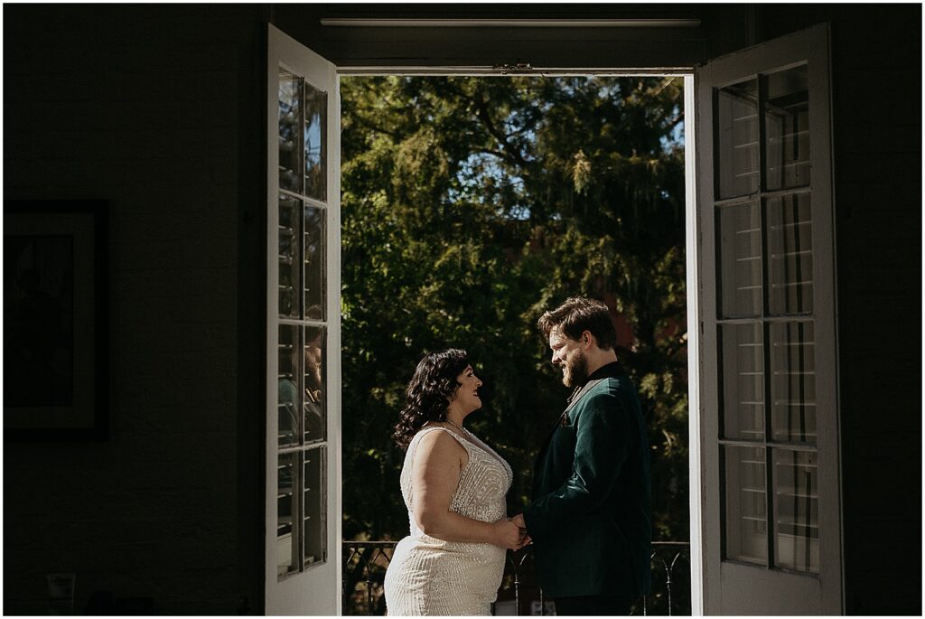 A New Orleans wedding photographer photographs a bride and groom through a set of balcony doors.