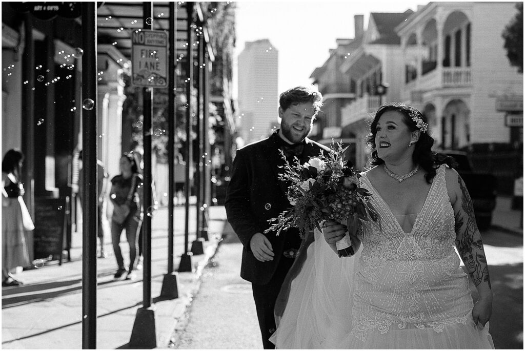 Bubbles fly past a bride and groom as they walk to their Baroness New Orleans wedding.