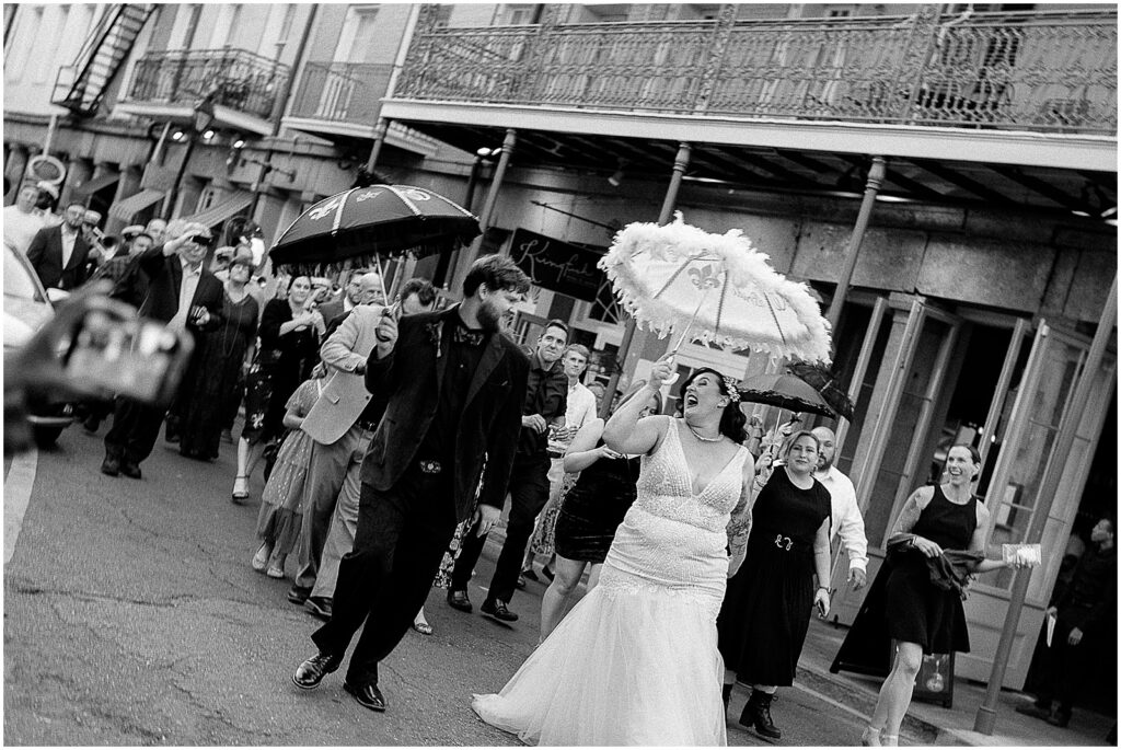 A bride and groom laugh and dance in a French Quarter street.