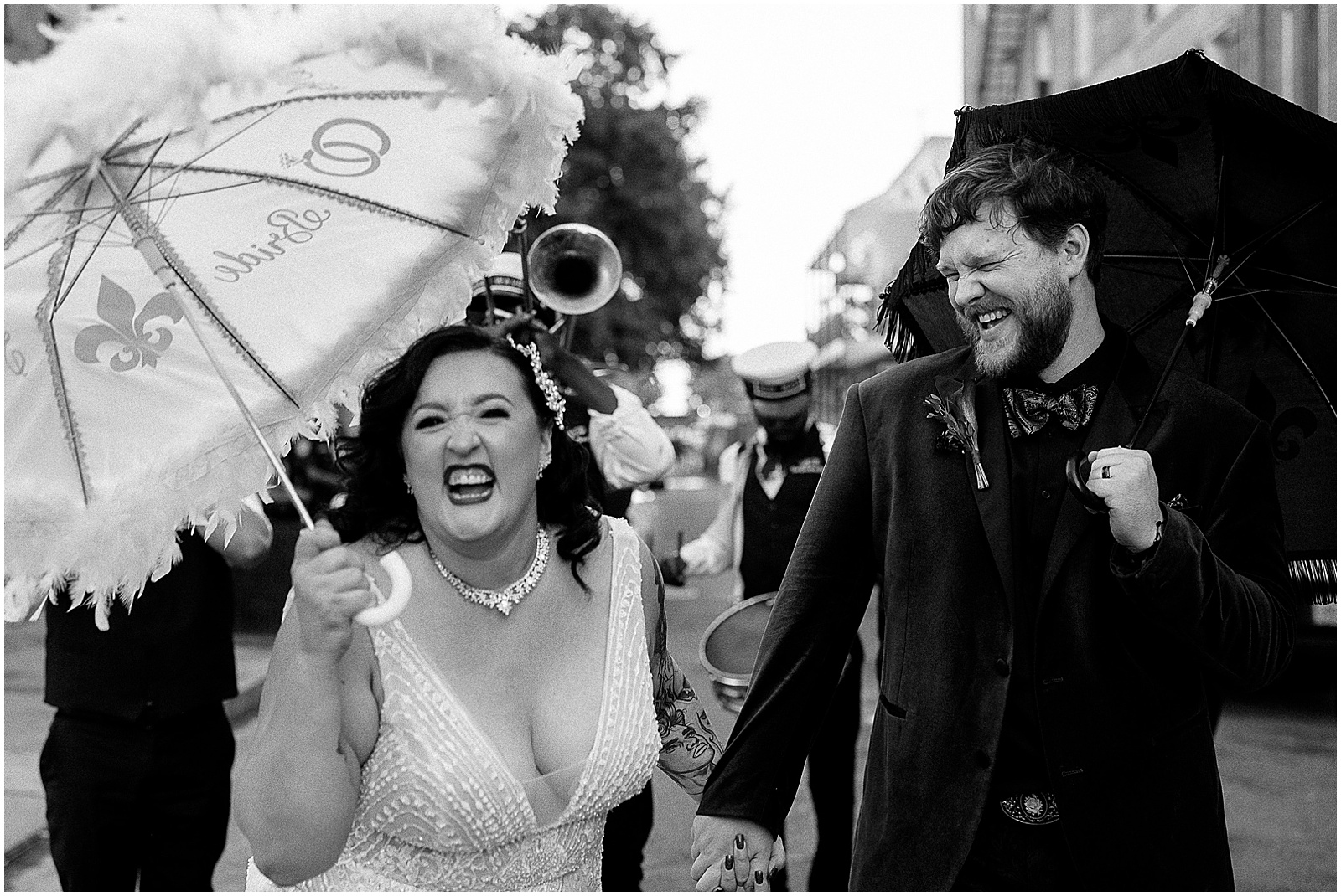 A bride leans towards a New Orleans wedding photographer smiling and waving a wedding umbrella.