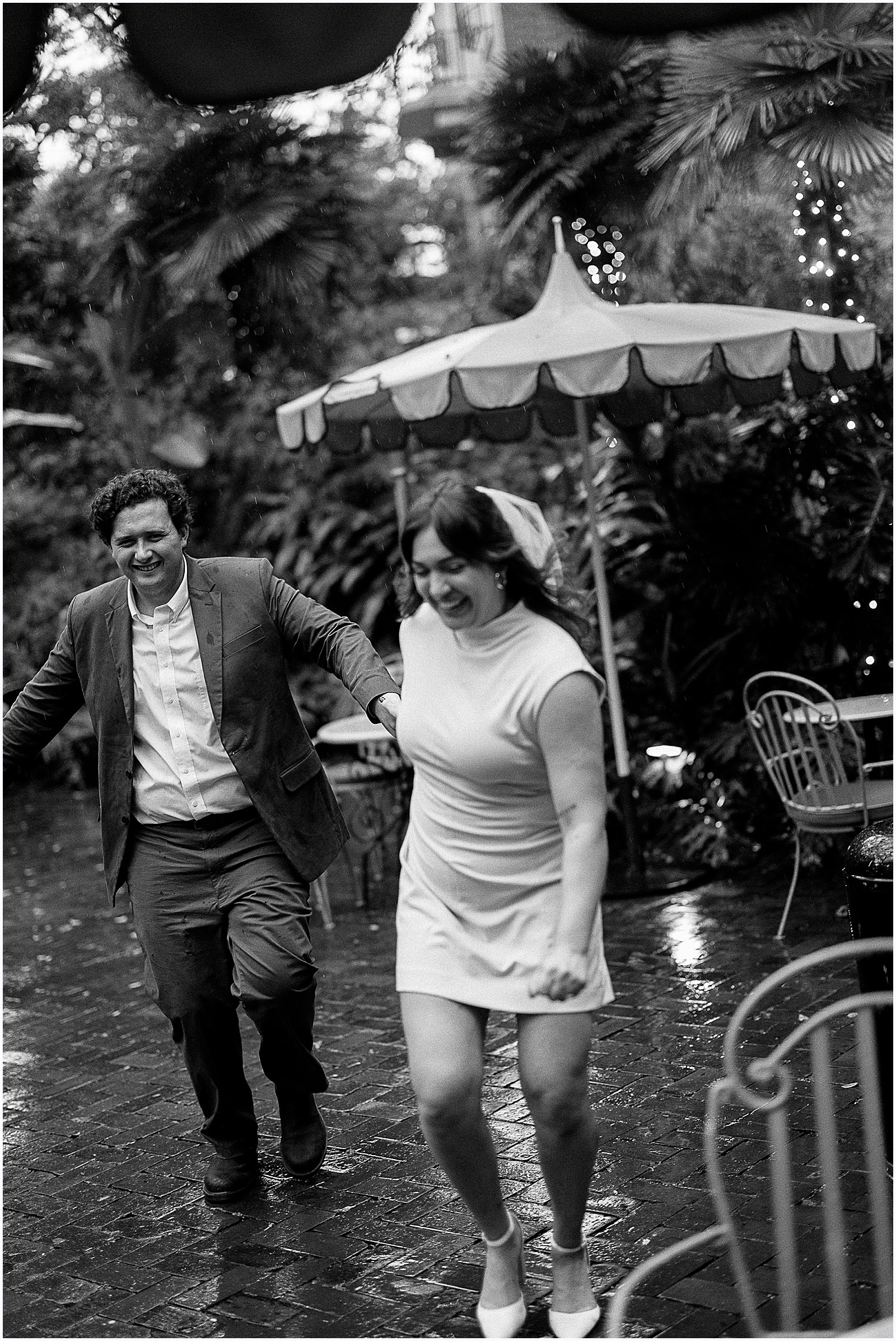 A man and woman run through the rain on the patio of the Columns Hotel in New Orleans