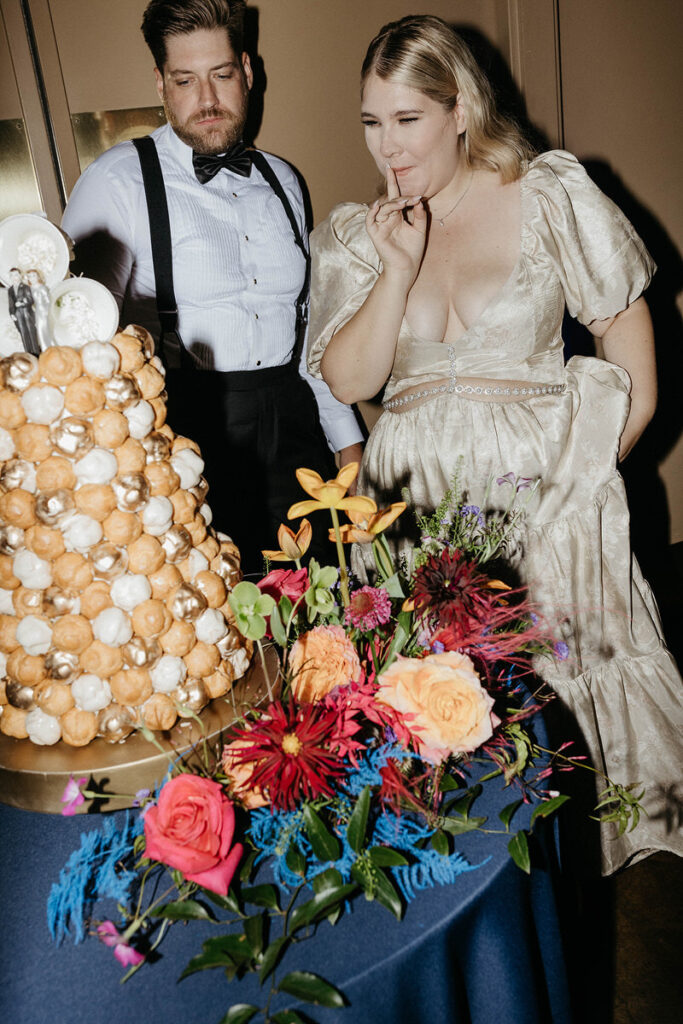 A newlywed couple pulling donut holes off of a tower of them 
