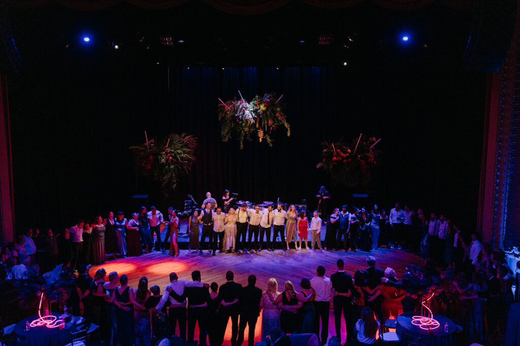 Wedding guests standing in a big circle around a dance floor 
