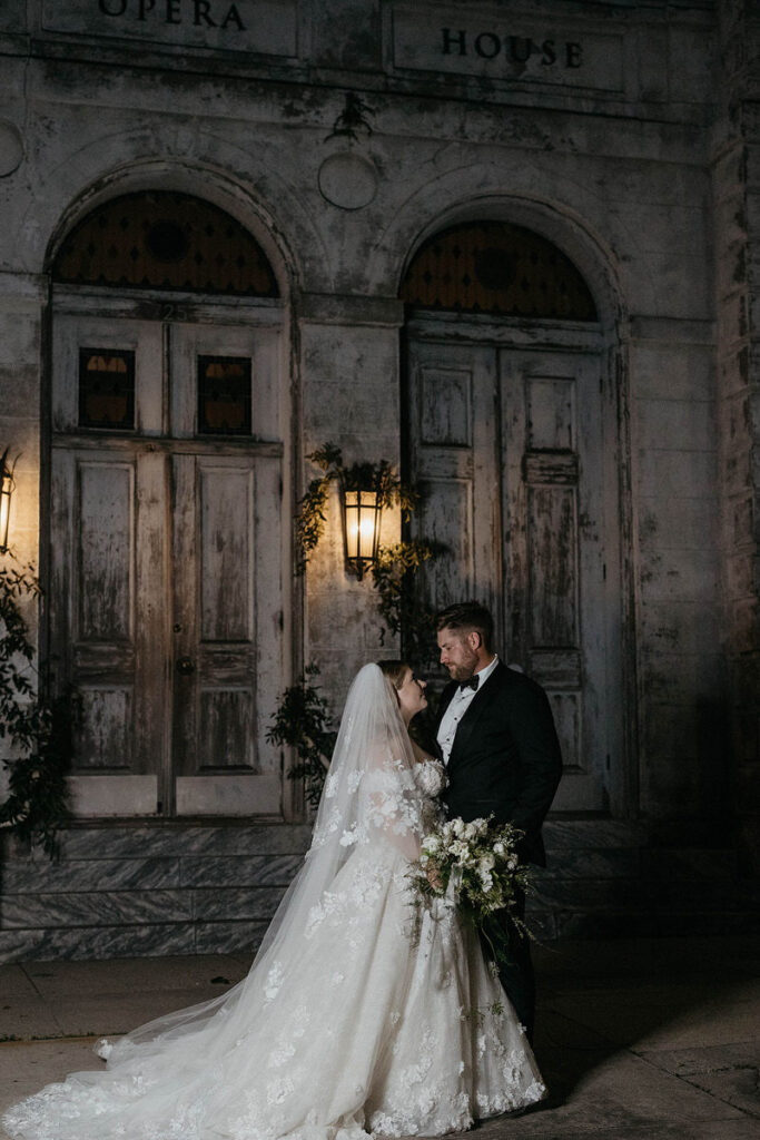 A newlywed couple standing close together smiling at each other 