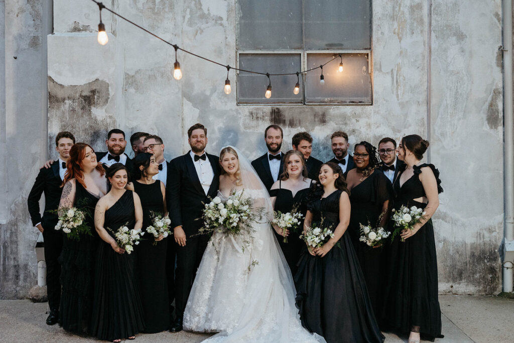 A newlywed couple with their wedding parties smiling 
