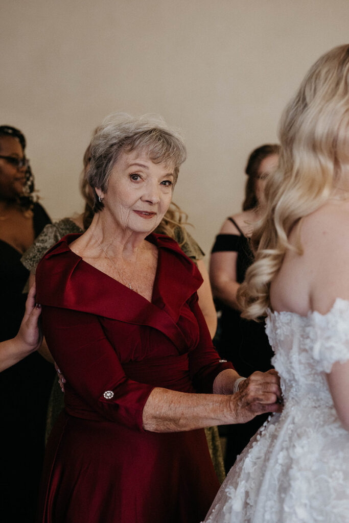 A person helping someone with their wedding dress 
