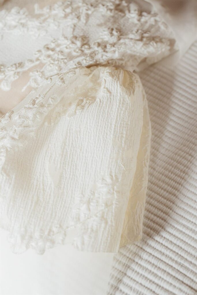 Close-up of a white textured fabric with intricate lace details.