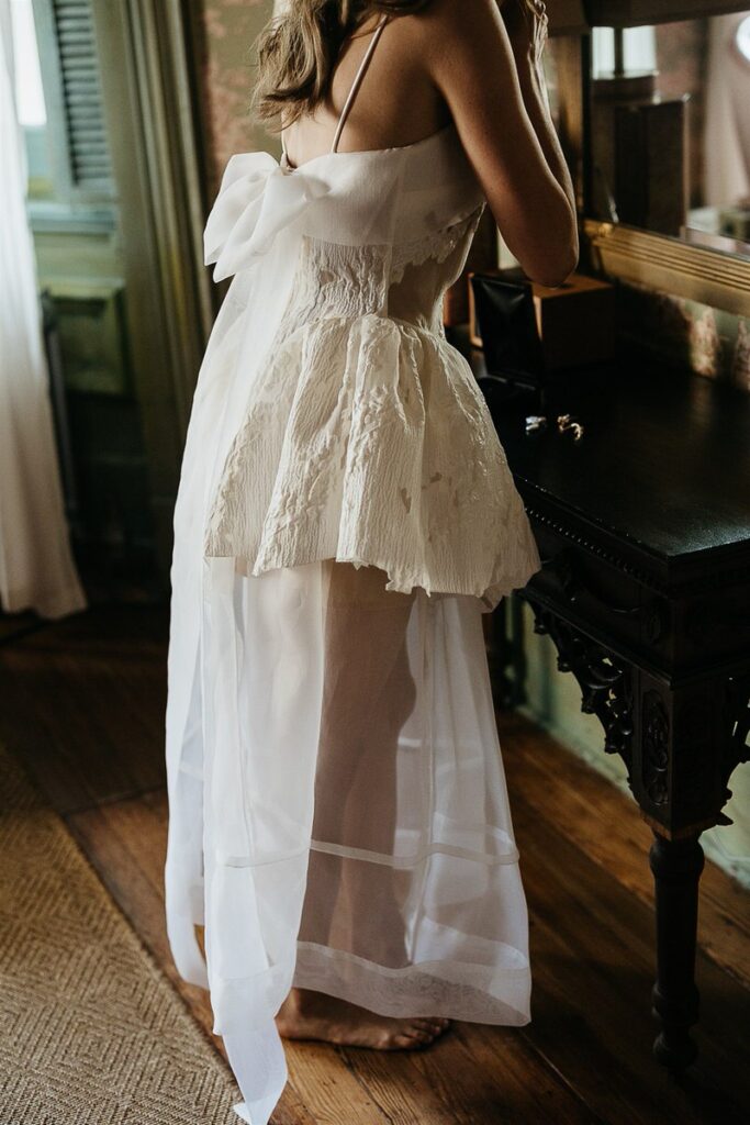 Close-up of the lower half of a bride's dress, showcasing the lace and sheer fabric details.
