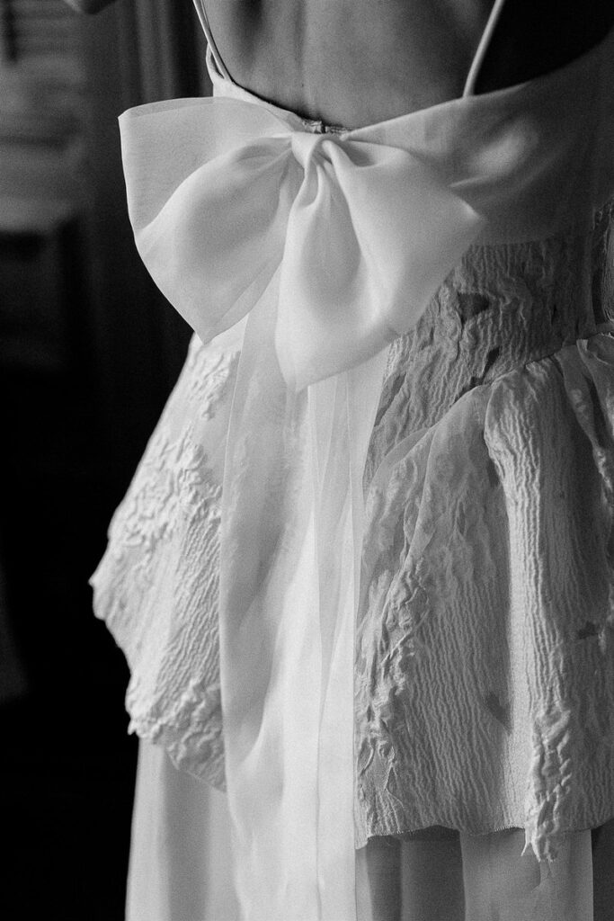 Close-up of the back of a wedding dress, featuring a large, elegant bow.
