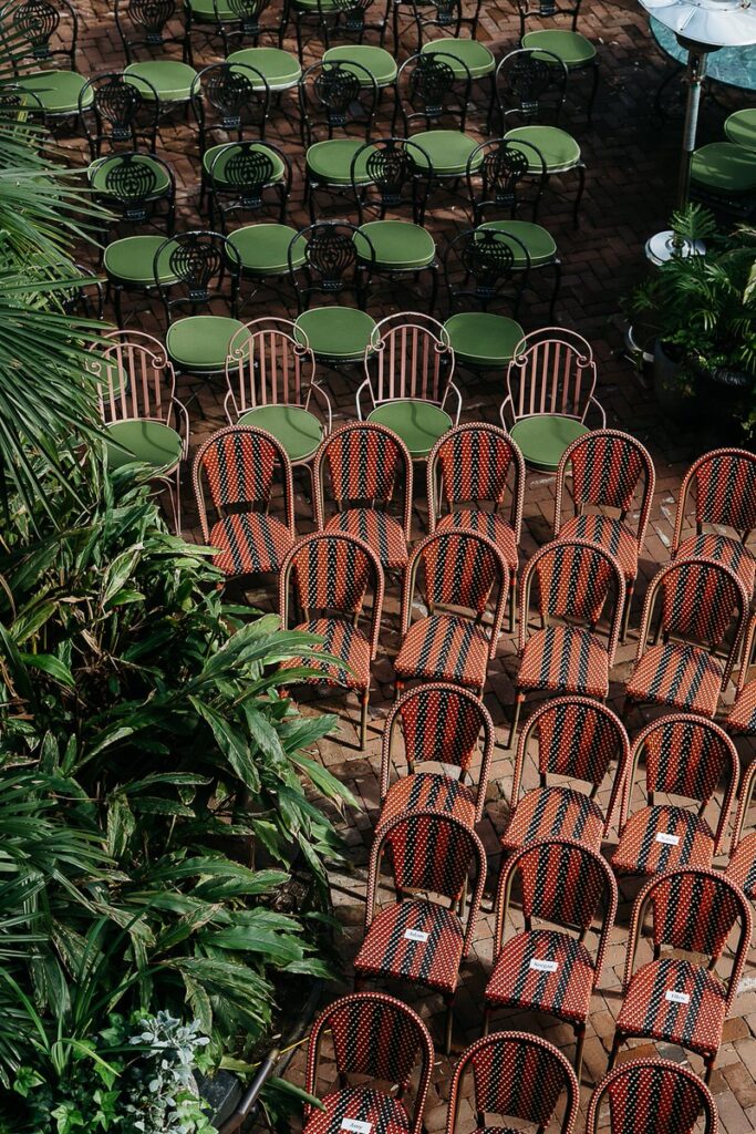 An aerial view of rows of chairs and tables set up for the wedding ceremony, with green and red chairs.
