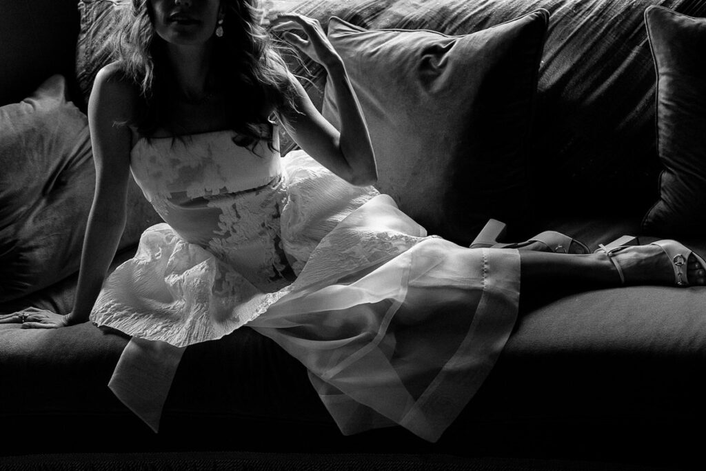 The bride in her dress, lounging on a sofa, with a moody and intimate lighting.
