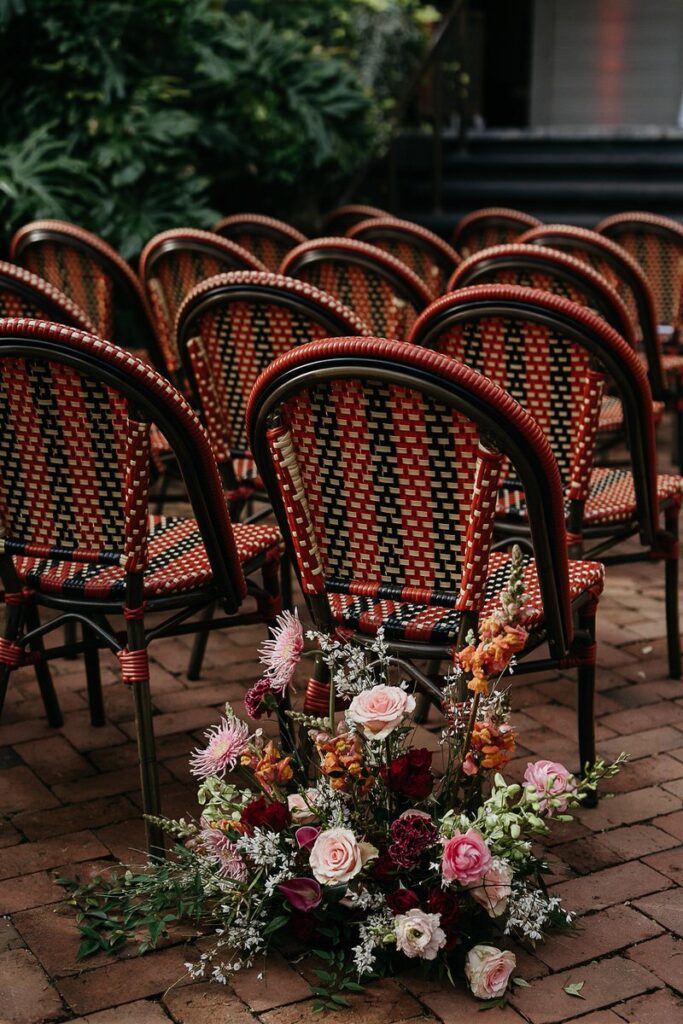 Rows of patterned chairs arranged for the wedding ceremony, with a floral arrangement at the end of the aisle.
