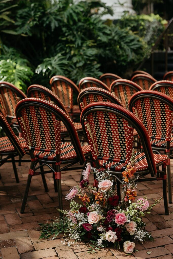 A view of the wedding ceremony seating arrangement, with a floral arrangement on the ground.
