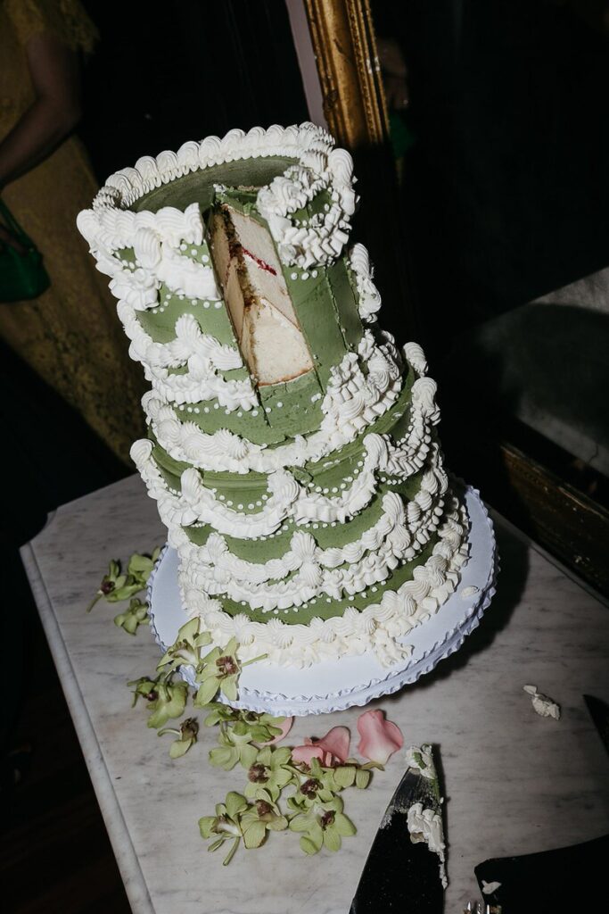 Close-up of the wedding cake with a slice removed, revealing the cake layers inside.
