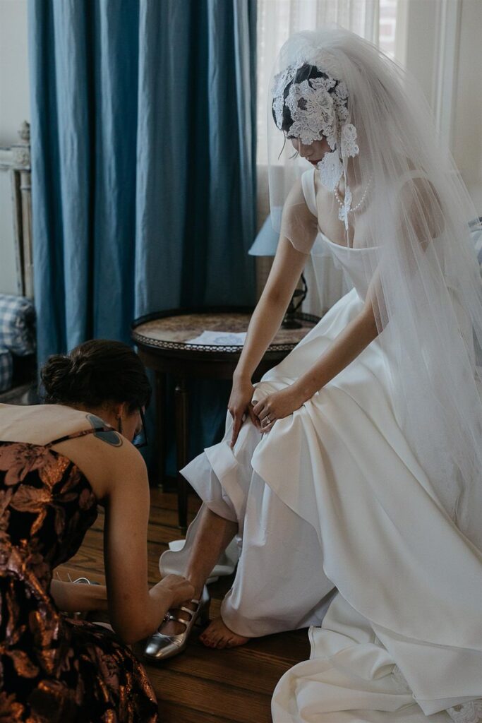 A person helping a bride put on shoes 