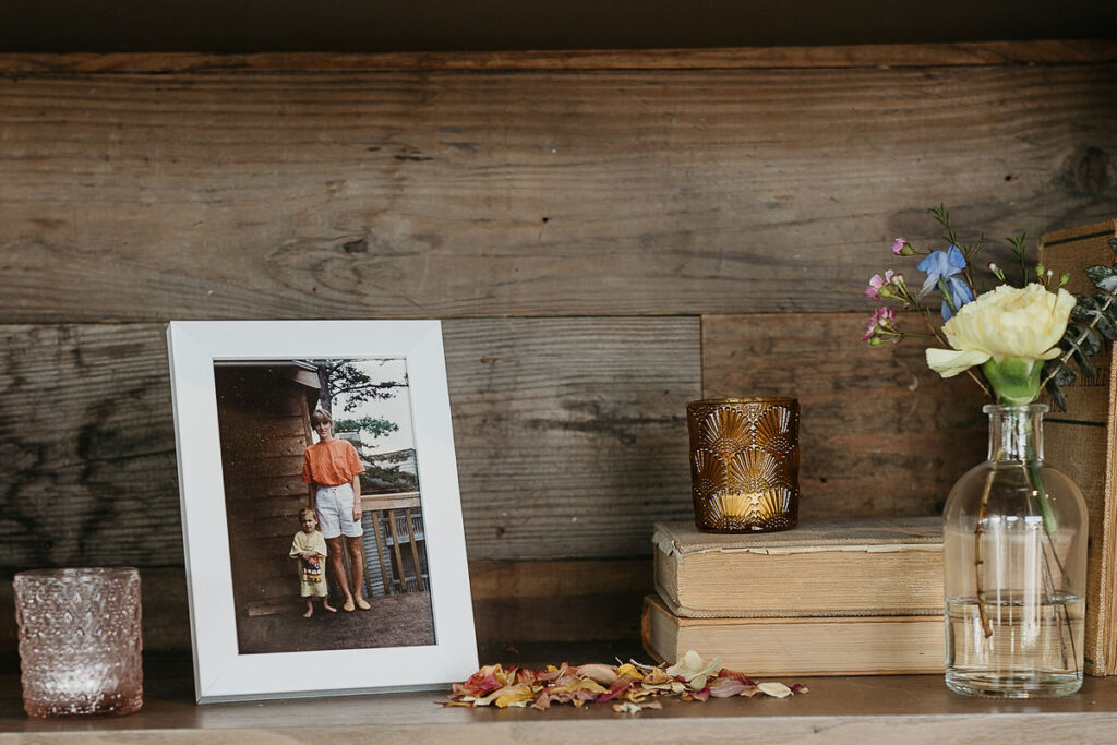 A picture frame on a table with flower petals and candles 