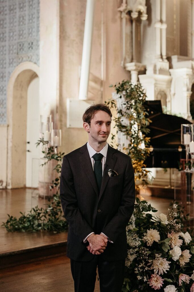 A groom crying with his hands clasped 