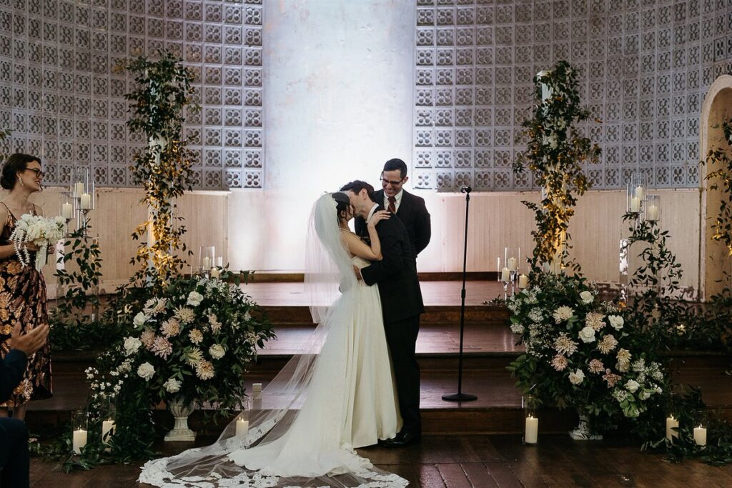 A bride and groom during their first kiss 