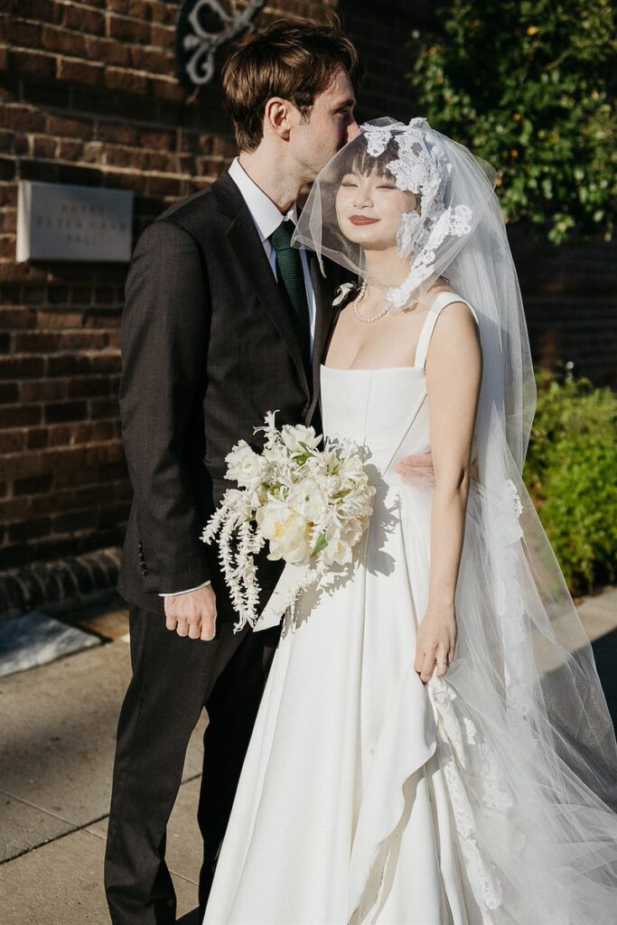 A groom kissing a bride's head 