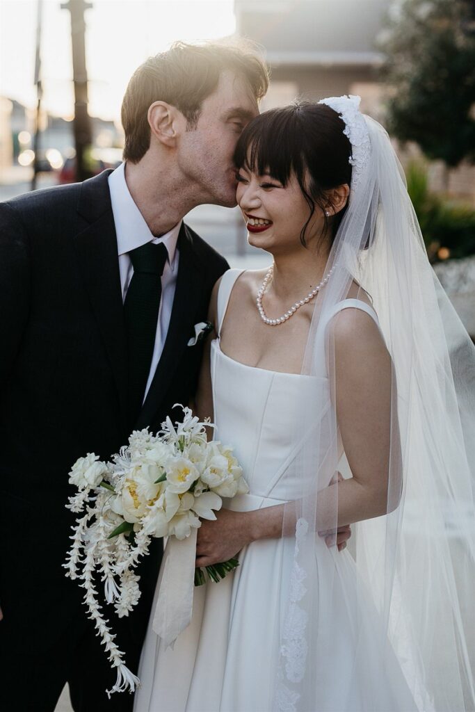 A groom kissing a bride's cheek 
