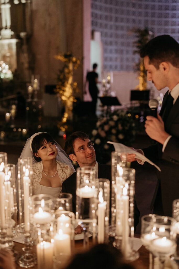 A person giving a speech next to the bride and groom 
