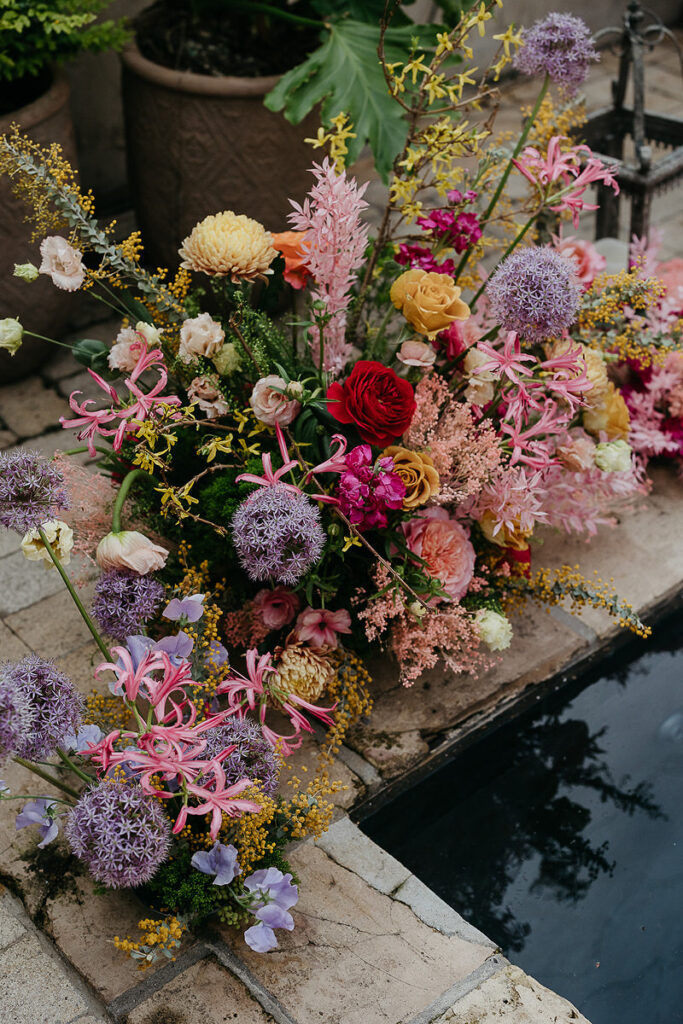 Floral arrangements on the ground next to a pool 