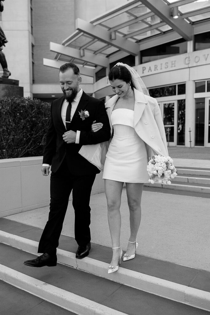 A newlywed couple walking down the stairs of city hall. 