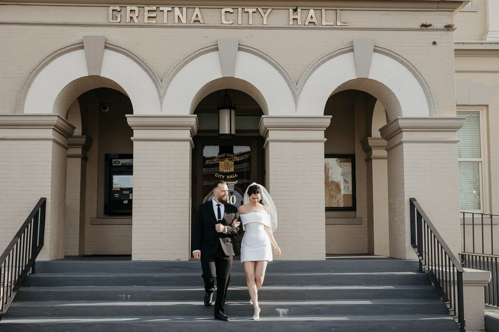 A newlywed couple walking down the stairs of city hall. 