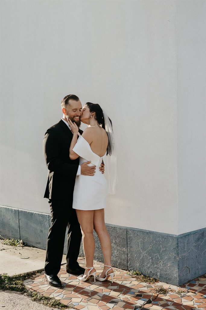 A person kissing their partner's cheek on their wedding day 