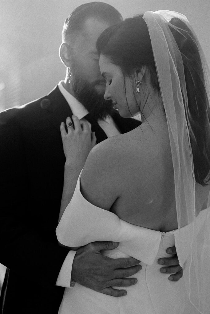 Black and white photo of a newlywed couple standing close together 
