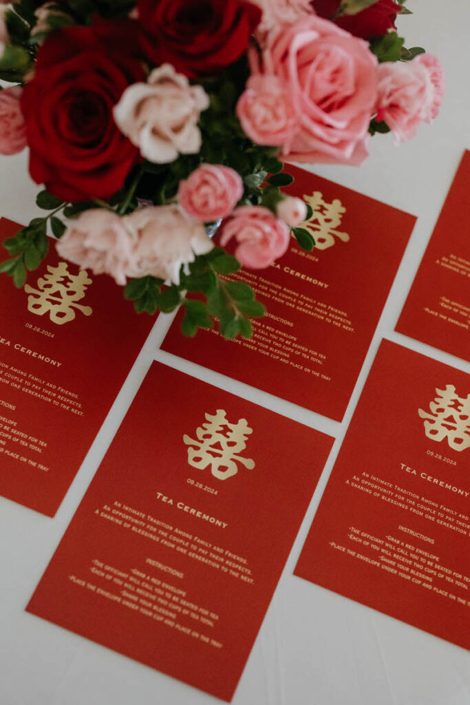 Wedding invitations laid out next to each other on a table with a floral arrangement 