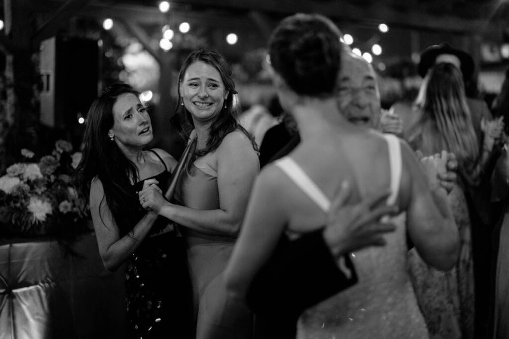 A person in a wedding dress dancing with an elderly person with wedding guests smiling along