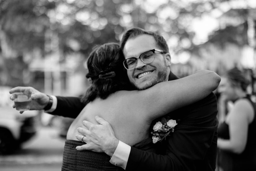 A newlywed smiling and hugging a wedding guest 