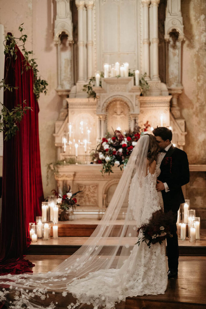 A newlywed couple standing close together as one kisses the other's cheek