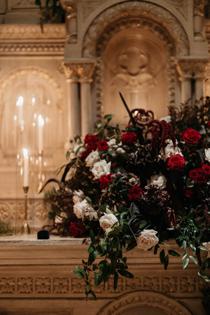A close up view of a moody floral bouquet with candles next to it