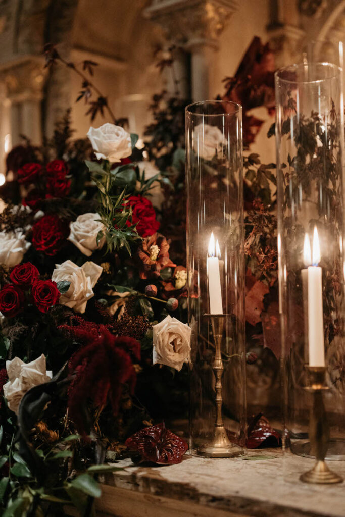 Tall candles lit next to moody floral bouquets