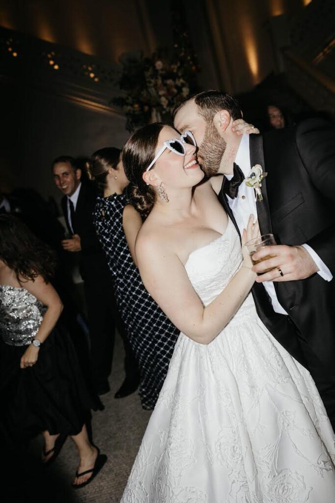 A person kissing their partner on the cheek during their wedding reception