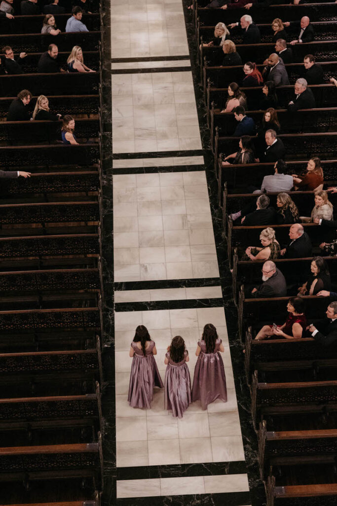 View looking down at three small girls walking down the aisle during a wedding