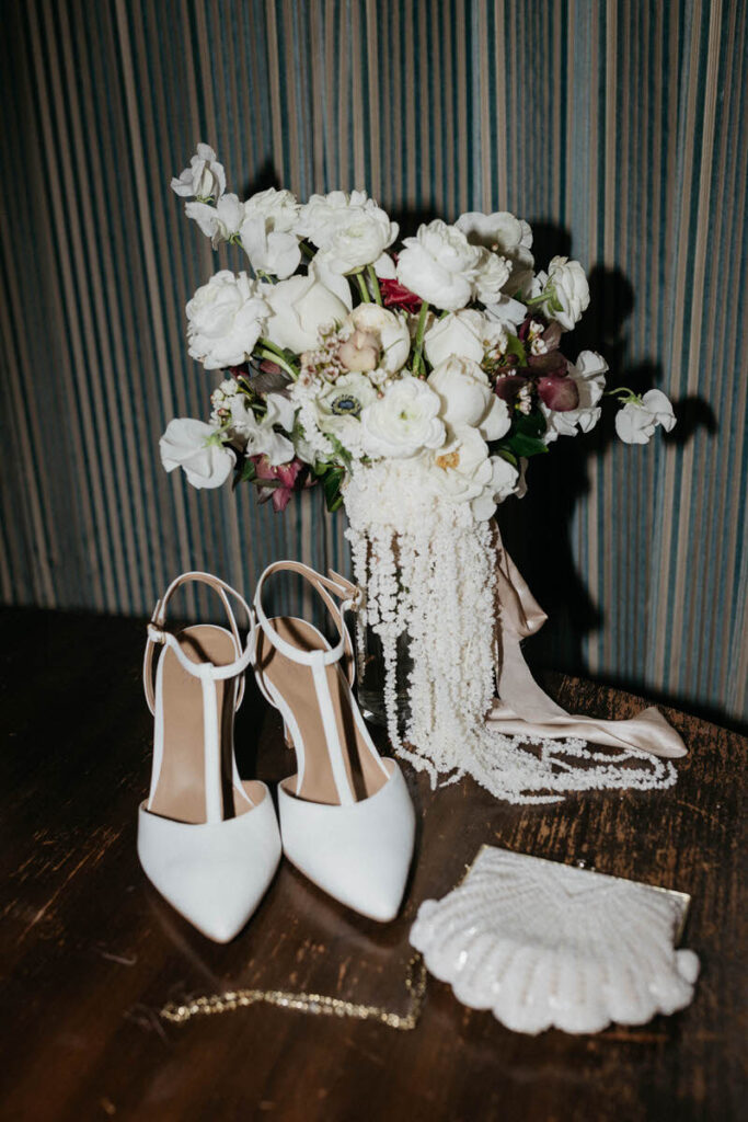 Heels, a purse, and a floral arrangement sitting on a table