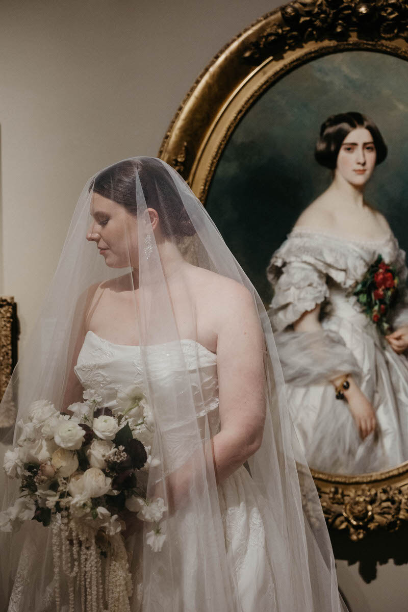 A person in a wedding dress looking off to the side with a veil covering their face