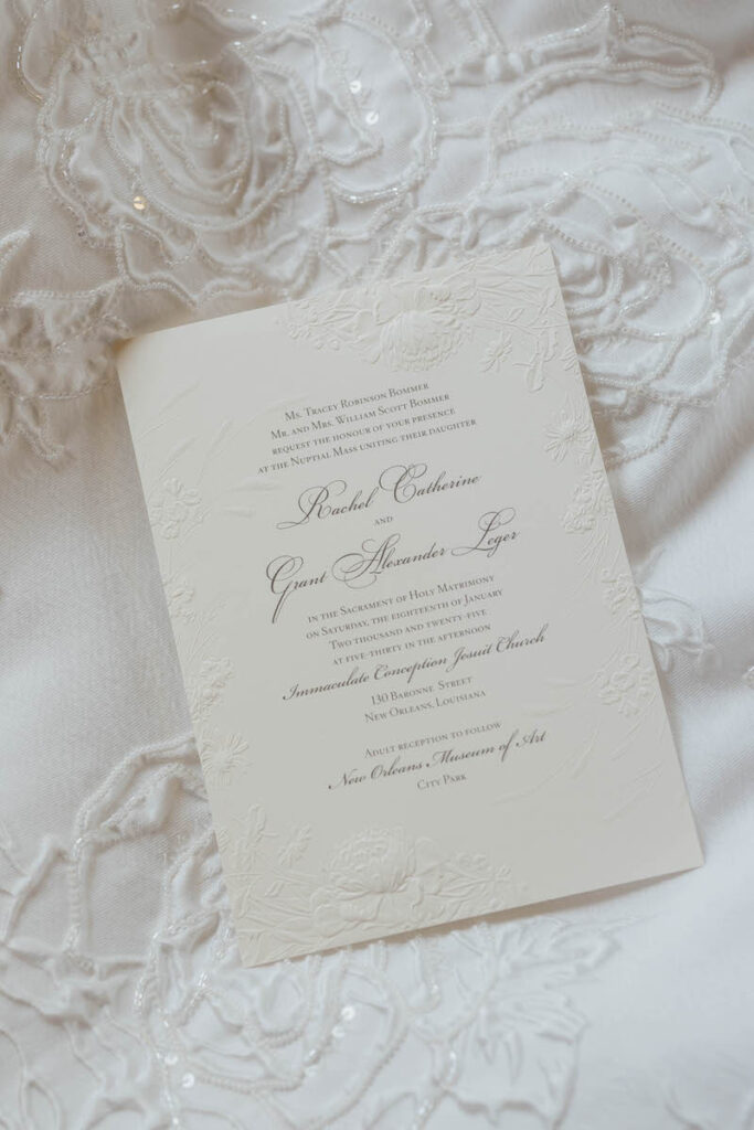 A wedding invitation laid on top of a veil