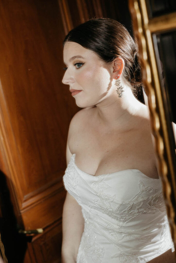 View of a person in a wedding dress leaning slightly looking in a mirror