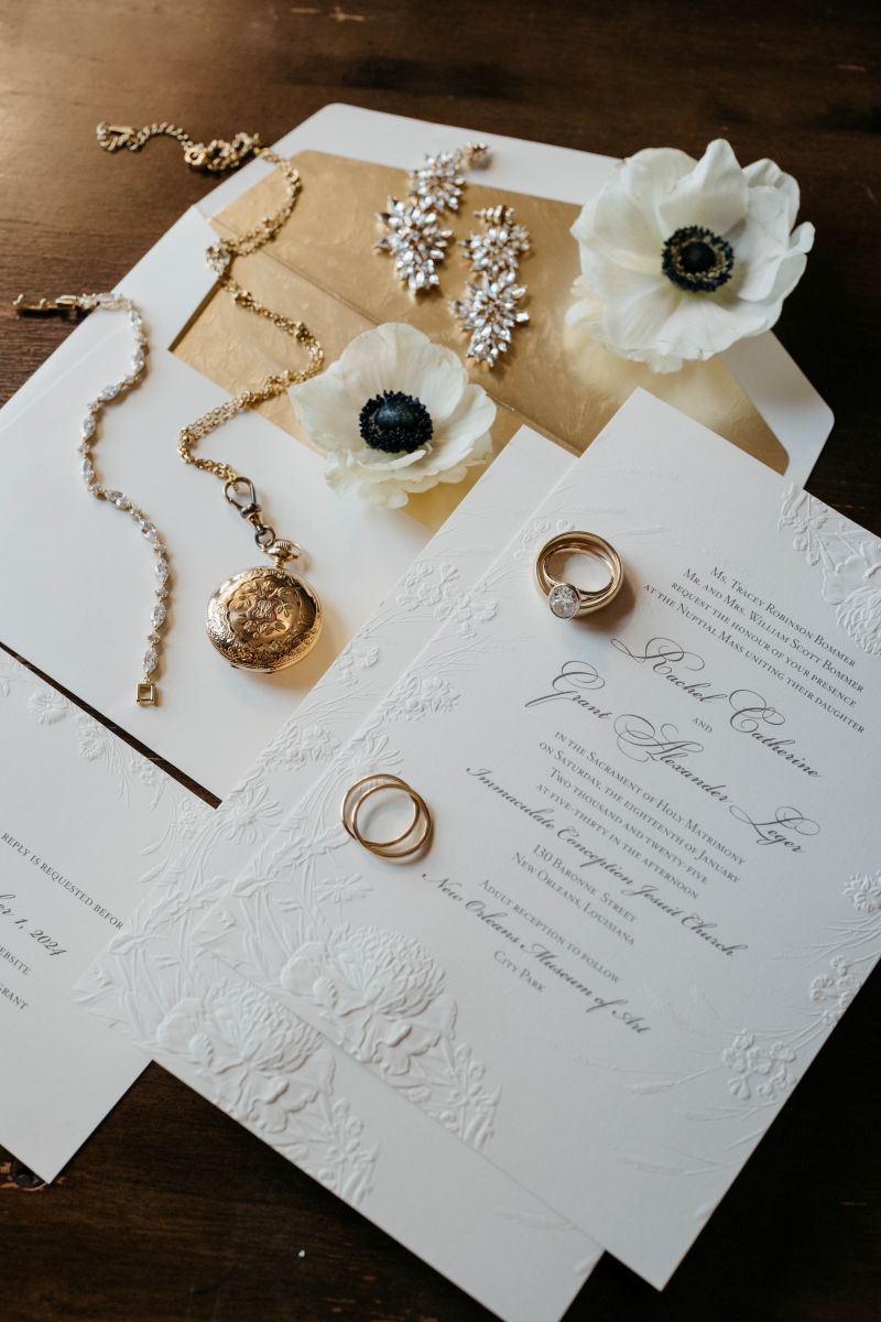 wedding details including a wedding invitations, rings, necklaces, and earrings