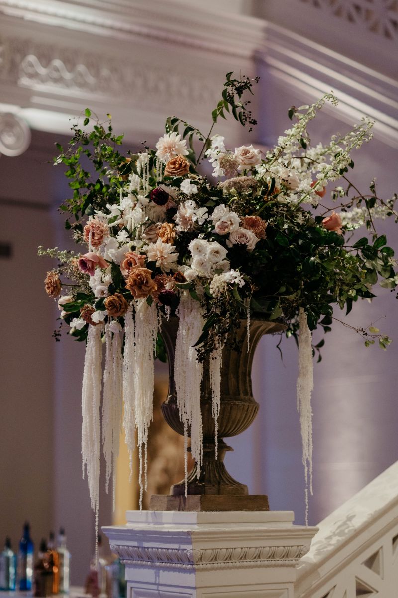an elegant floral arrangment on top of a column at the end of a staircase