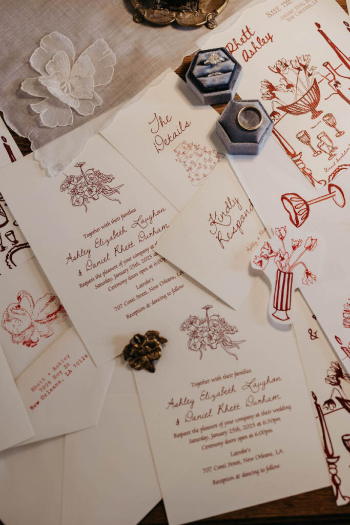 Wedding invitations, jewelry, and small flower petals laid out on a table