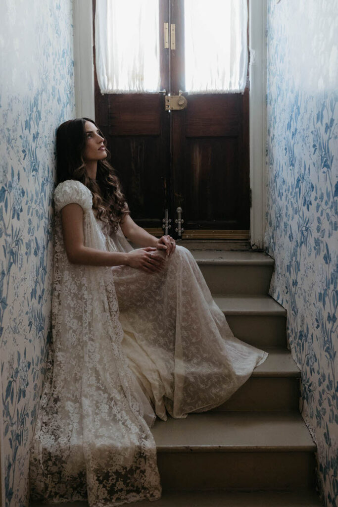 A person in a wedding dress sitting in a small staircase